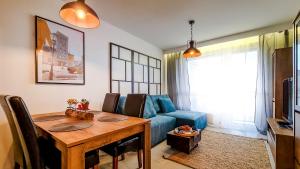 uma sala de estar com uma mesa e um sofá azul em Apartment Przyfabryczny Księży Młyn - Garaż - Klimatyzacja - FV em Lódź