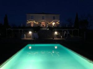 uma piscina à noite com uma casa ao fundo em The Villa em Monteroni dʼArbia