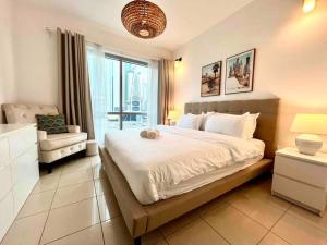 ein Schlafzimmer mit einem Bett, einem Stuhl und einem Fenster in der Unterkunft Sunkissed holiday homes Modern 2BR Apt near JBR beach, Marina mall & DMCC metro in Dubai