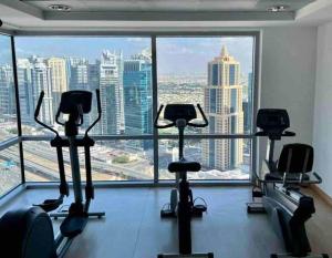 a gym with cardio machines in front of a large window at Sunkissed holiday homes Modern 2BR Apt near JBR beach, Marina mall & DMCC metro in Dubai