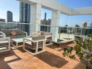 eine Terrasse mit Sofas und Tischen auf einem Gebäude in der Unterkunft Sunkissed holiday homes Modern 2BR Apt near JBR beach, Marina mall & DMCC metro in Dubai