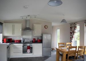 a kitchen with white cabinets and a table with chairs at King Richards Country Lodges in Earl Shilton