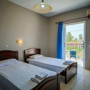 a bedroom with two beds and a sliding glass door at Perkes Hotel Complex in Laganas