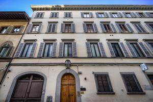 wysoki biały budynek z oknami i drewnianymi drzwiami w obiekcie Hs4U Ricasoli Luxury apartment near Duomo N.2 we Florencji