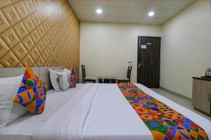 een slaapkamer met een groot bed met kleurrijke kussens bij FabHotel Heaven Agya Ludhiana in Ludhiana