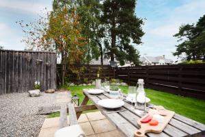 a wooden picnic table in a backyard with a fence at Rose Cottage - Seasgair Lodges in Carrbridge