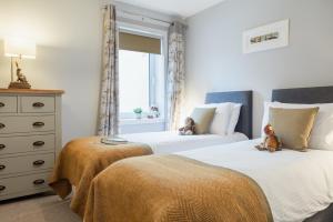 Duas camas com ursos de peluche sentados num quarto em Rose Cottage - Seasgair Lodges em Carrbridge