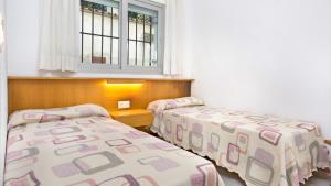 Dos camas en una habitación pequeña con ventana. en Mas Vermey nº 3, en Calella de Palafrugell