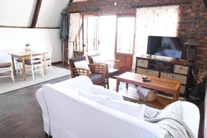 a living room with a white couch and a tv at Bonnie View Game Lodge in Hilton