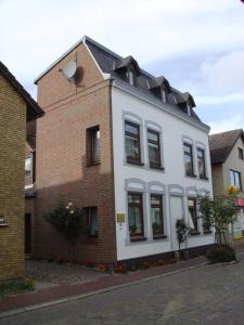 a white building on a street next to a brick building at Ferienwohnung mit Balkon und Schleiblick in Maasholm