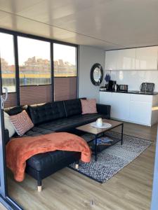 a living room with a black leather couch and a table at Hausboot Fjord Vineta mit Biosauna in Barth in Barth