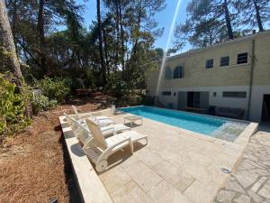 einen Pool mit zwei Liegestühlen neben einem Haus in der Unterkunft Pyla sur mer proche plages appartement avec piscine in Pyla-sur-Mer