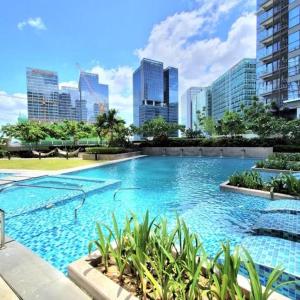 a large swimming pool in a city with tall buildings at BGC, Uptown Parksuites Tower 2 in Manila