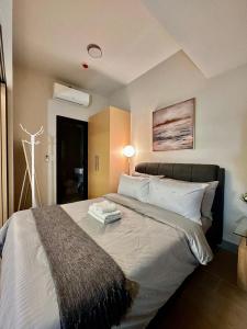 um quarto com uma cama grande com lençóis brancos e almofadas em BGC, Uptown Parksuites Tower 2 em Manila