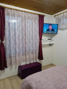 1 dormitorio con 1 cama y TV de pantalla plana en At Chorbadzhiykata, en Kalofer
