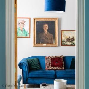 um sofá azul numa sala de estar com retratos na parede em North Lodge & River Cabin em Banchory