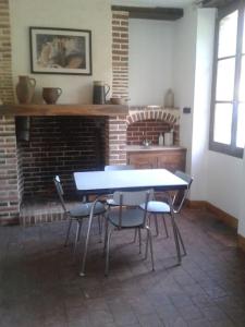 にあるGîte en pleine nature calme & tranquillité assuréeのレンガ造りの暖炉付きの部屋(テーブル、椅子付)