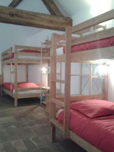 een kamer met 3 stapelbedden met rode lakens bij Gîte en pleine nature calme & tranquillité assurée 