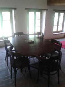 een houten tafel en stoelen in een kamer met ramen bij Gîte en pleine nature calme & tranquillité assurée 