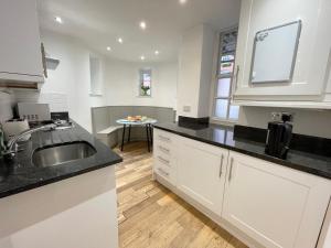 cocina con armarios blancos, fregadero y mesa en Westminster Apartment near River Thames en Londres