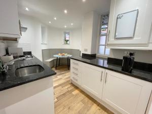 a kitchen with white cabinets and a sink and a table at Westminster Apartment near River Thames in London