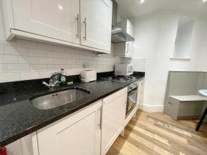 una cocina con armarios blancos y fregadero en Westminster Apartment near River Thames en Londres