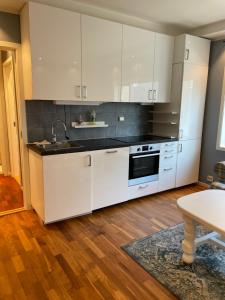 eine Küche mit weißen Schränken, einer Spüle und einem Tisch in der Unterkunft Eiganesveien 1 in Stavanger