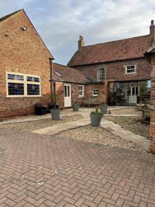 uma casa de tijolos com uma entrada de tijolos em frente em Newsham Grange Farm em Thirsk