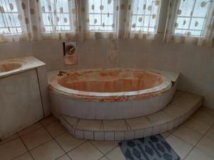 una grande vasca in un bagno con lavandino di THATCH HAVEN GUEST HOUSE a Mahikeng