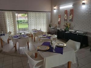 una sala da pranzo con tavoli bianchi e sedie bianche di THATCH HAVEN GUEST HOUSE a Mahikeng