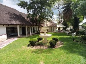 a garden with a birdbath in the yard of a house at THATCH HAVEN GUEST HOUSE in Mahikeng