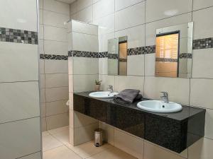 a bathroom with two sinks and two mirrors at TaTe Village in Windhoek