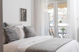 a white bed with gray pillows and a window at F & B Collection - 3 Bedroom Penthouse in Thessaloniki