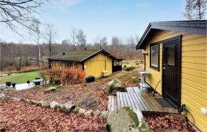 een klein geel huis met een houten terras bij Stunning Home In sljunga With House A Panoramic View in Åsljunga