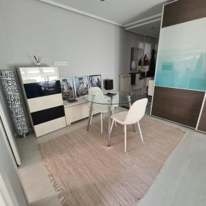 a dining room with a glass table and white chairs at Ático Somo Beach in Somo