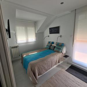ein Schlafzimmer mit einem Bett und zwei Fenstern in der Unterkunft Ático Somo Beach in Somo