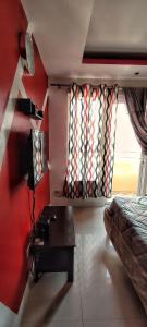 a bedroom with red walls and a bed and a table at Birch Tower Private Studio with Manila City Metro View in Manila
