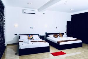 two beds in a room with white walls at Forest Dew Udawalawa in Udawalawe