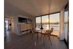 une salle à manger avec une table, des chaises et une grande fenêtre dans l'établissement Hausboot Fjord HAVEN mit Biosauna in Barth, à Barth