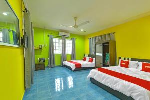 una camera con due letti e pareti gialle di OYO 90744 Bari Indah Beach Resort a Kuala Terengganu