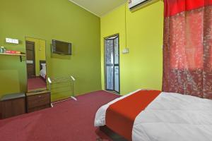 1 dormitorio con paredes verdes, 1 cama y espejo en OYO 90744 Bari Indah Beach Resort, en Kuala Terengganu