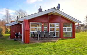 einen roten Schuppen mit einem Tisch und Stühlen im Hof in der Unterkunft Strandpark 11 in Schönhagen