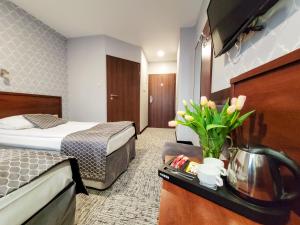 ein Hotelzimmer mit einem Bett und einem Tisch mit Blumen in der Unterkunft Hotel Fero Express POKOJE KLIMATYZOWANE AC in Krakau
