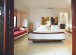 a bedroom with a large white bed and a red couch at Qunci Villas Resort in Senggigi