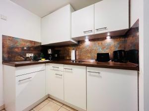 a kitchen with white cabinets and a sink at Modernes Apartment mit Blick zur Frauenkirche in Dresden