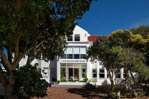 una casa blanca con árboles en primer plano en Cape Agulhas Guest House, en Agulhas