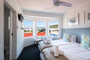 a hotel room with two beds and a balcony at Cape Agulhas Guest House in Agulhas