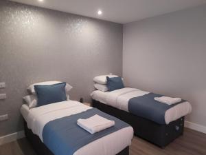 a room with two beds with towels on them at Apartments Heathrow - Hounslow in Cranford