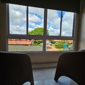 una ventana en una habitación con 2 sillas y vistas al mar en Mensú Grand Hotel en Puerto Iguazú