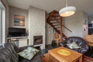 uma sala de estar com mobiliário de couro e uma lareira em Abbestederweg 24A Callantsoog em Callantsoog
